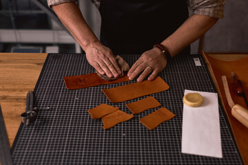 Obraz premium man preparing pieces of leather for sewing. close up cropped photo