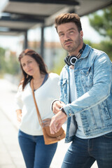 man standing on railway station platform and looking at watch