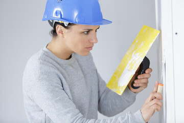 working woman plastering  painting walls inside the house