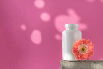 Mockup is a white jar with pills or vitamins on a podium. Vitamins for women. Copy space