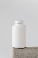  Mockup is a white jar with pills or vitamins on a podium. Medical preparations.