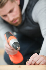 man assembling furniture at home using a cordless screwdriver