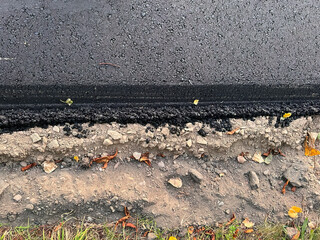 The close-up texture of the fresh hot asphalt on the new road. Road construction. A large layer of fresh hot asphalt. Layer of asphalt raw material in a shallow depth of field.