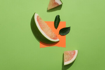 Vibrant pomelo and green leaves on a green background with an orange acrylic sheet. Explore the...