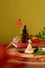 Front view of an unbranded brown serum bottle is displayed with pomelo, fresh flowers, green leaves and props on a wooden table. Skin care with natural products.