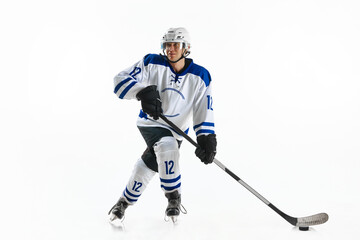 Young man, hockey athlete in motion, standing on rink with stick, training, playing against white...