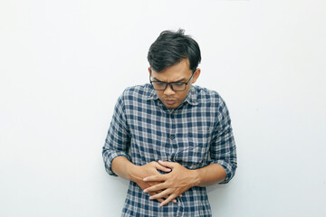 Portrait of Asian Indonesian man placing his hands on stomach for stomach ache or hungry gesture - obrazy, fototapety, plakaty