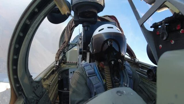 A pilot in a helmet inside the cockpit of a fighter