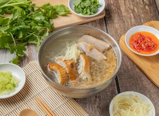 Duck vermicelli Soup with chilli sauce, noodles, spoon and chopsticks served in bowl isolated on napkin top view of hong kong food