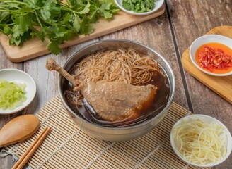 Angelica Duck Noodles Soup with chilli sauce, noodles, spoon and chopsticks served in dish isolated on napkin top view of hong kong food