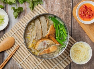 Duck meat rice noodles with chilli sauce, noodles, spoon and chopsticks served in dish isolated on napkin top view of hong kong food