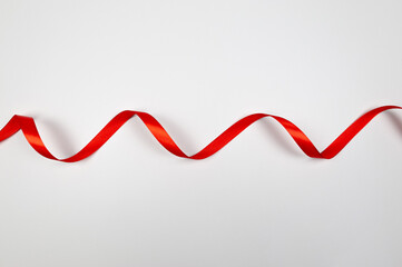 Top view of red ribbon on white background. Shiny rolled fabric, silk and satin material. Copy...