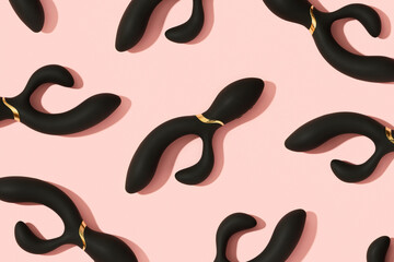 Black vibrator on the peach pink background. Sex toys for adults. Pattern - obrazy, fototapety, plakaty