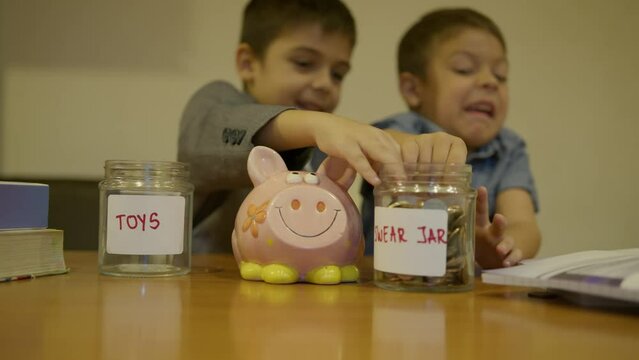 Financial education. Children savings. Two brothers in disagreement for the jar name, emergency fund or swear jar. Older prother stals piggy bank and runs awayslow motion. High quality 4k footage