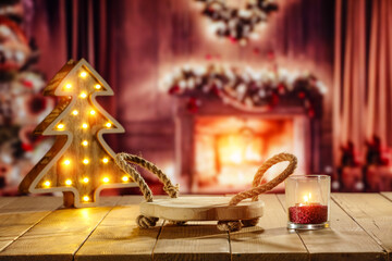 Wooden retro yellow table and blurred background of window sill. Christmas tree and empty space for your decoration. Natural light and magic time. Mockup background and cold december time.