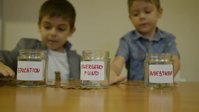 Childrens savings education, budgeting. Brothers sorting coins between education jar, emergenci fund and investment jar. High quality 4k footage