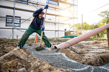 Man spreading fresh concrete for a building foundation