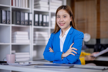 Young Asian business woman office worker analyst sitting at desk working on laptop thinking on project plan, analyzing marketing or financial data online, watching elearning webinar.