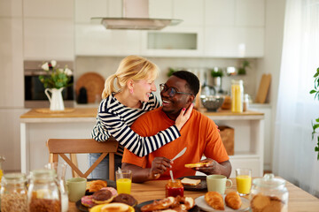 Multiracial couple having tender moment over breakfast at home