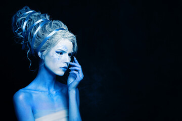 Nice cool cold woman with blue and white body art, carnival makeup and hairstyle on black background