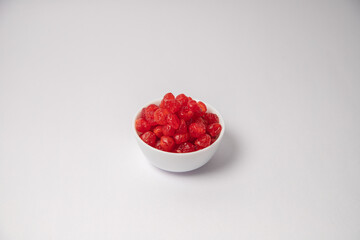 Dried red cherry fruit on white bowl with white background, Dried cherries scattered on the white background in a black bowl or vessel