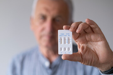 Older man is holding a antigen combo test (cov-19, flu a b and rsv).