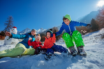 Family jump in snow make snowy splashes over sunny mountains