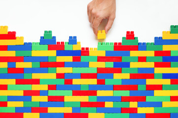 Man's hand Placing the Final Detail on Wall from Colorful plastic brick blocks. Constructing...