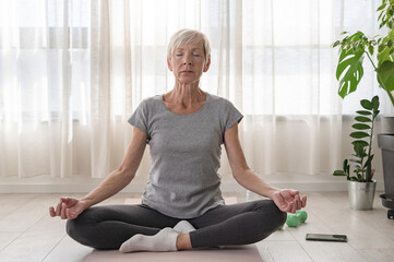 Active elderly woman practicing yoga indoors