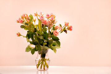 A bouquet in a transparent vase of apricot-colored bouquet roses, the trend color of apricot crash...