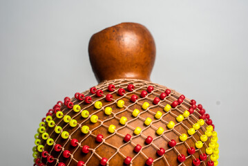 Traditional music percussion instrument - shekere with red and yellow beads covering the dried gourd