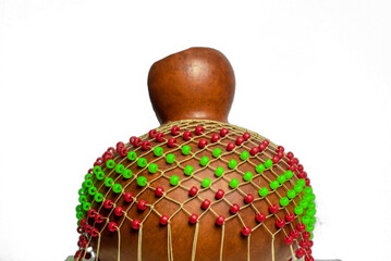 Traditional music percussion instrument - shekere with red and yellow beads covering the dried gourd