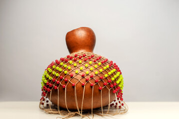 Traditional music percussion instrument - shekere with red and yellow beads covering the dried gourd