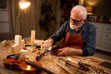 Senior carpenter craftsman making violin instrument