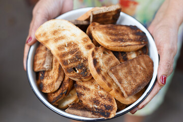 Woman's holding bread toasts from grill in the bowl