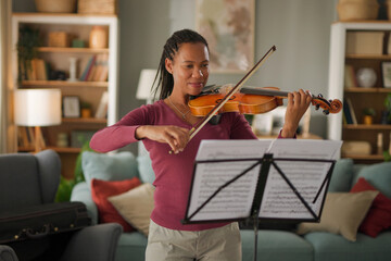 Mid adult woman playing violin at home