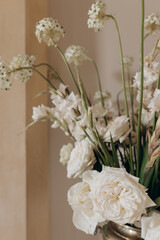 Close-up of fragment of luxurious composition in white tones against beige wall, wedding floristry. 