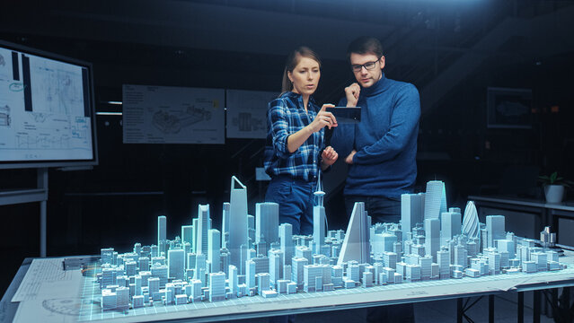 Architect and Engineer have Discussion, Use Augmented Reality Smartphone to Design Sustainable 3D Megalopolis City Model. Futuristic Office with Architectural Designers. Graphical VFX on Image.