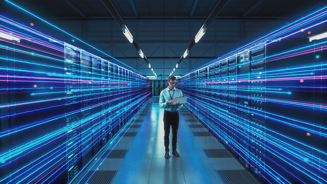 Futuristic Concept: Data Center Chief Technology Officer Holding Laptop, Standing In Warehouse, Information Digitalization Lines Streaming Through Servers. SAAS, Cloud Storage, Online Service