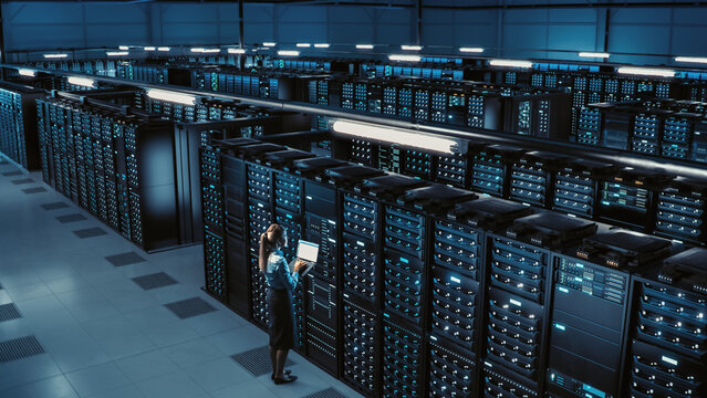 3D Computer Graphics: Big Data Center Female Chief Technology Officer Using Laptop Standing In Warehouse, Activates Servers, Information Digitalization Starts. SAAS, Cloud Computing, Online Service