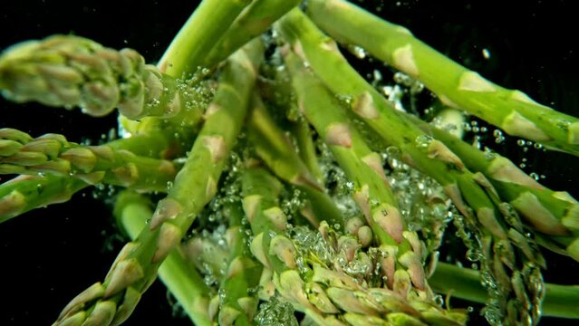 Super slow motion of falling asparagus into water. Isolated on black background. Filmed on high speed cinema camera, 1000fps.