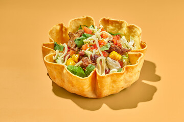 Taco salad in tortilla bowl with beef, cheese, corn and lettuce