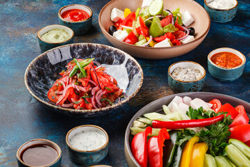 Dish with vegetables, peppers, tomatoes and greens, plates with vegetable salads and various types of sauces