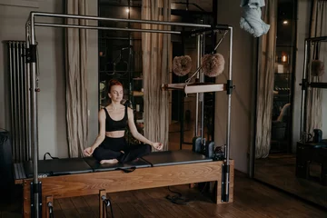 Foto op Plexiglas Young fit woman sitting in lotus position on trapeze table © VK Studio