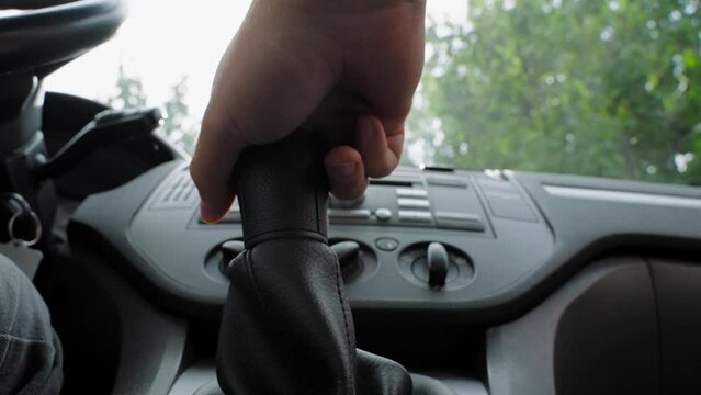 interior of a modern American car, view of the gear lever. close-up of a man's hand shifting gears in a car with a manual transmission on a dark sunny day, the sun's rays break through the window