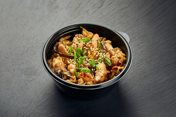 Traditional Asian dish, chicken or pork with rice and mushrooms in a plastic bowl - obrazy, fototapety, plakaty