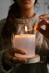Woman holding and lighting a selenite candle in her hands