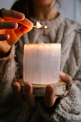 Woman holding and lighting a selenite candle in her hands
