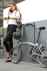 Obraz na płótnie Canvas Smart businesswoman ride bicycle in downtown. Environmentalist commuting by cycling reduce carbon footprint global warming. Bike to work eco friendly alternative transportation green energy vehicle
