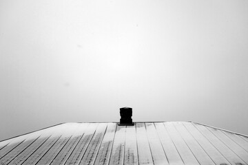House roof with chimney covered with snow. Black and white